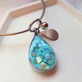 Narukvica od hirurškog čelika sa plavim priveskom od epoksi smole u obliku suze.