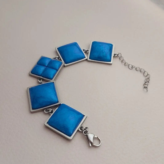 Geometrijska narukvica sa plavim kvadratnim privescima.